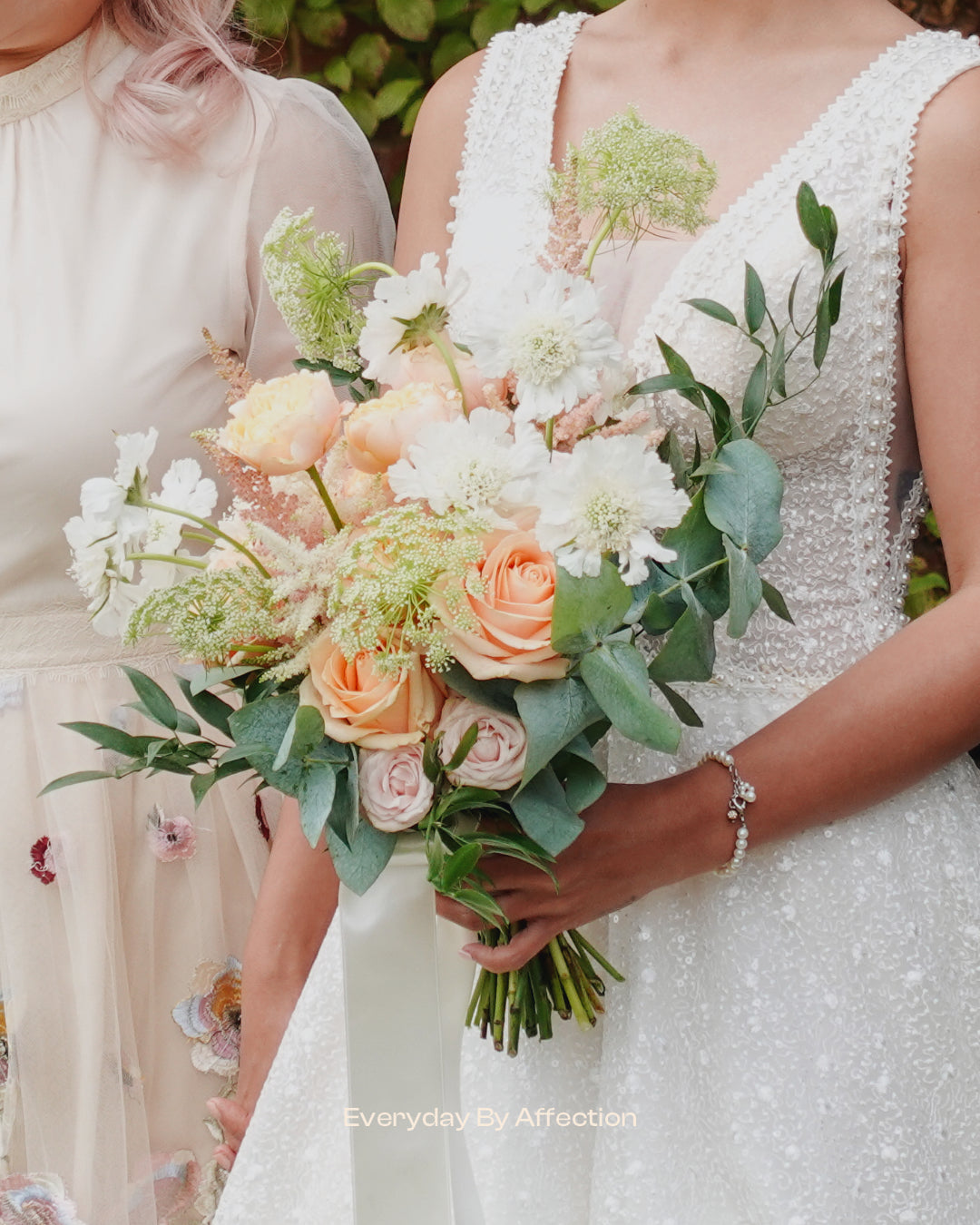 a bride holding a luxury bridal bouquet in white and pink flowers with green leaves