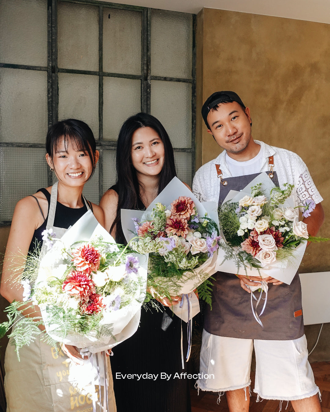 people holding hand tied bouqutes in a floristry class