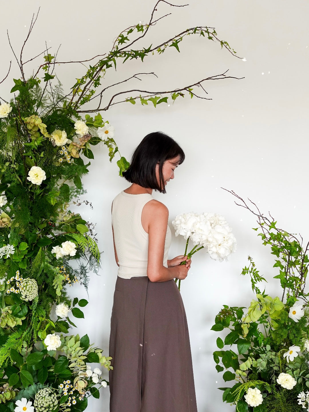 a girl standing in the middle of flower pillar