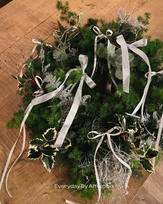 a gril hanging a christmas wreath in front of a christmas tree