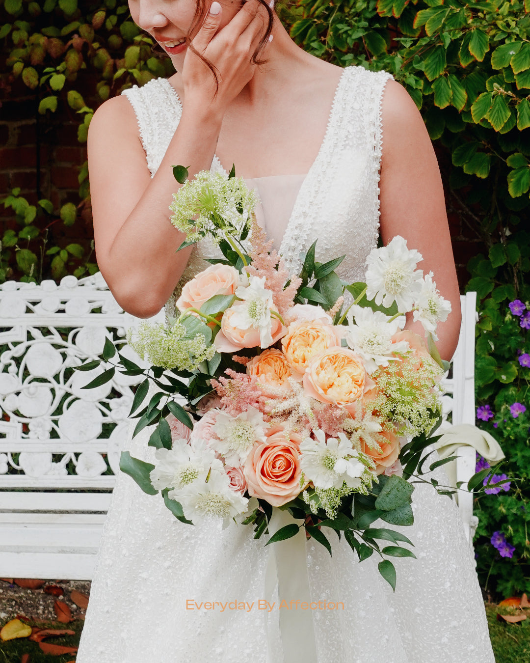 a bride holding a bridal bouquet in apricot pink roses