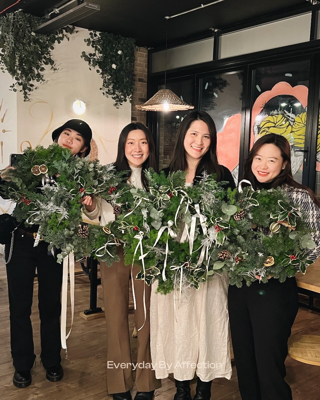 girls holding handmade Christmas Wreath with ribbons and ornaments