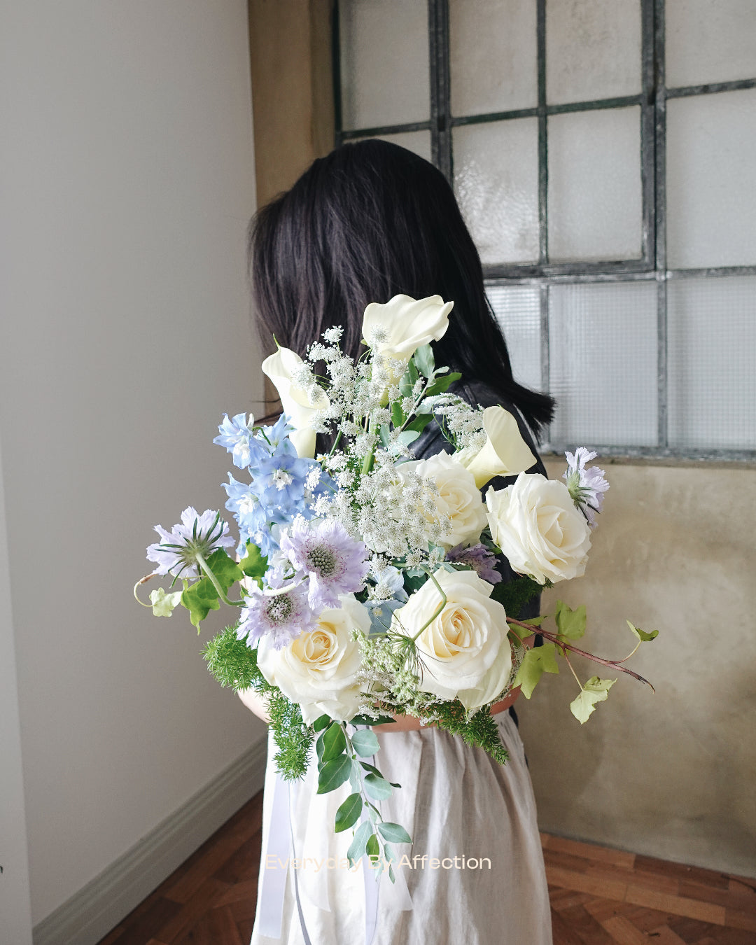 hand tied bridal bouquet in white roses blue delphinium purple scabiosa and white calla lilies