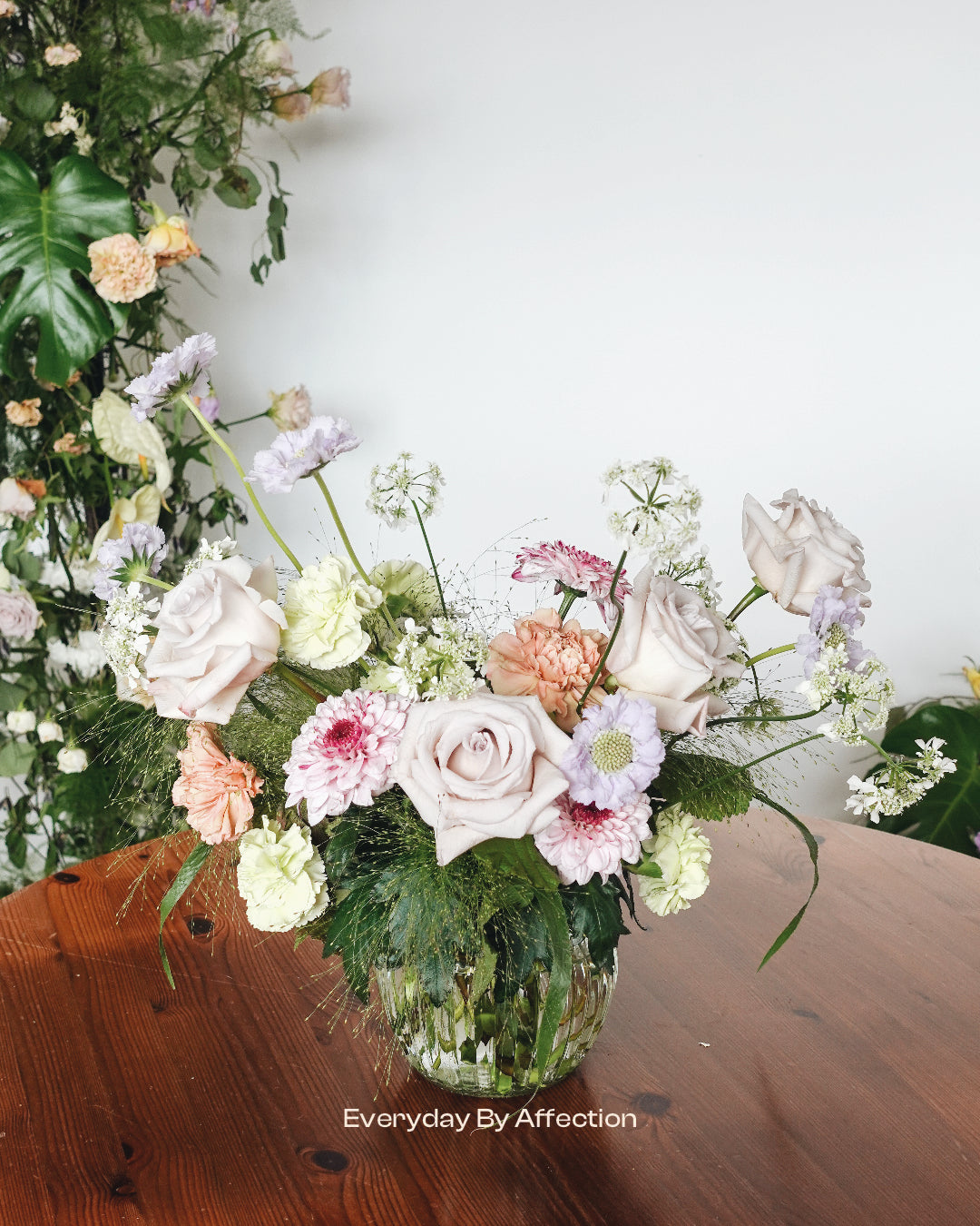 dusty rose flower centrepiece in a clear glass on a wooden table