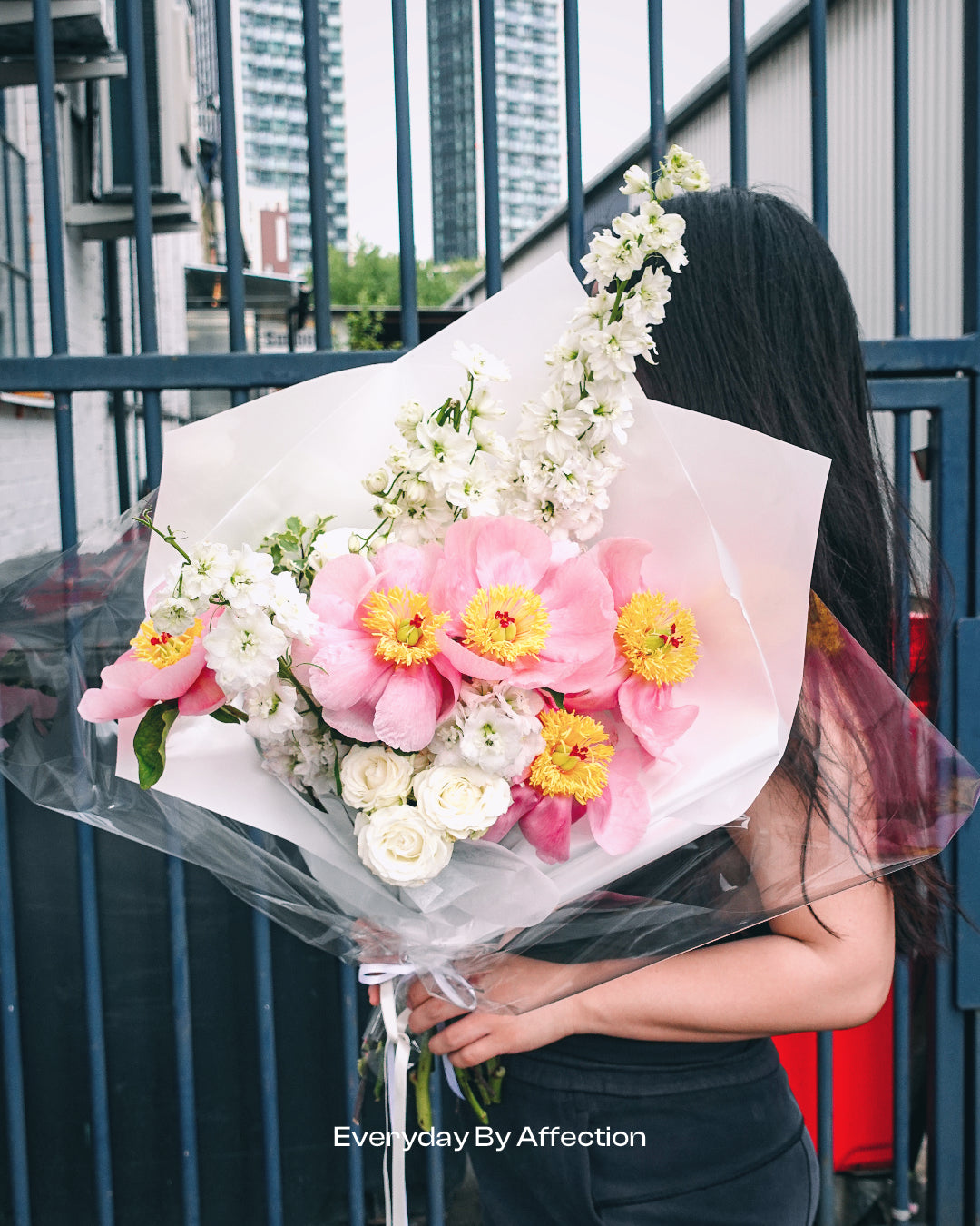 a girl holding a bouquet in pink peonies