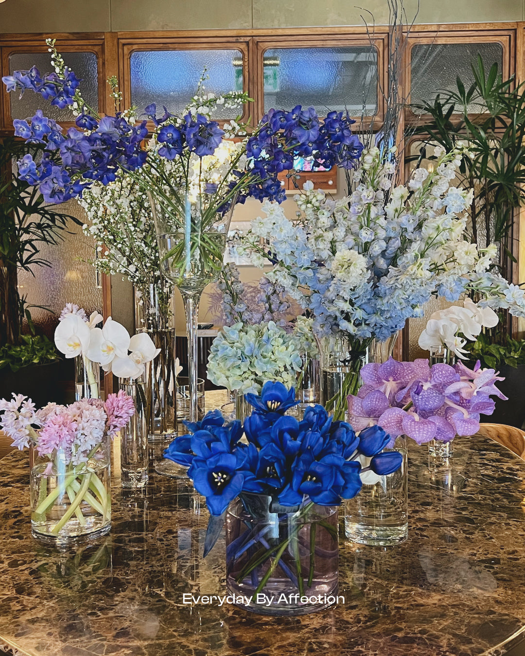 blue and purple flowers in glass on a hotel lobby table