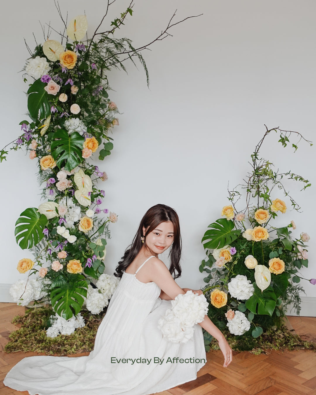 a bride standing in front of a flower arch